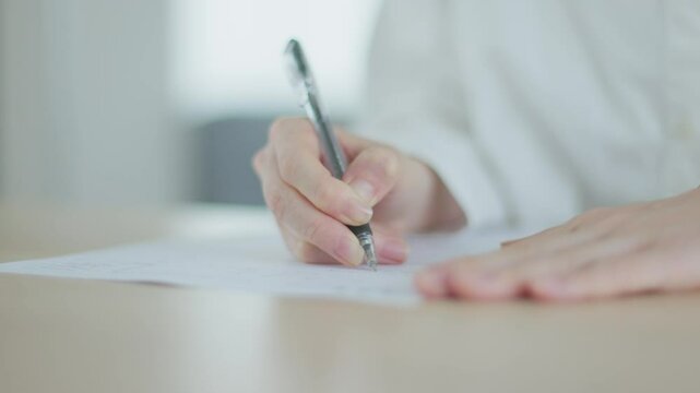 リビングの机にて書類にサインをする日本人女性