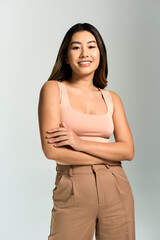 A woman with long dark hair smiles and stands with her arms crossed in front of her.