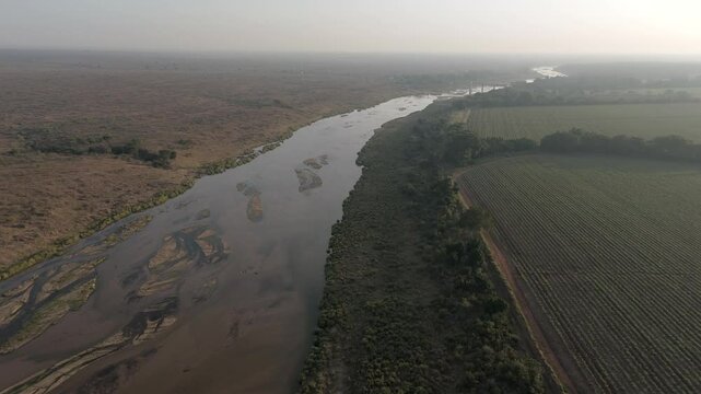 High-flying drone view of seasonal or ephemeral crocodile river by farmlands bordering the Kruger National Park. South Africa.