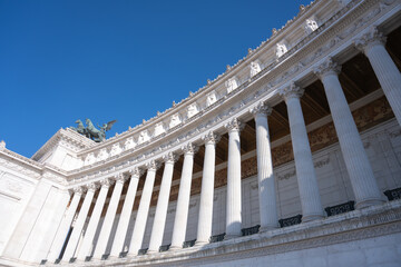 A low-angle view of the Vittoriano in Rome, showcasing its intricate white marble columns and decorative architectural details. Rome, Italy