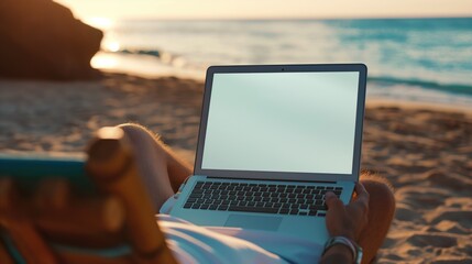 Mockup image of a man using laptop with blank white desktop screen while sitting on a beach. The concept of freelancing and vacationing. The concept of workaholism
