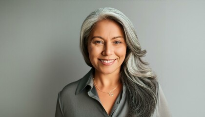 Happy smiling stylish confident 50 years old Asian female professional standing looking at camera at gray background