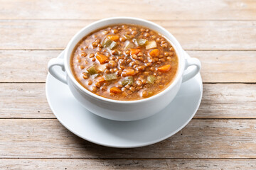 Lentil soup with vegetables in bowl on wooden table