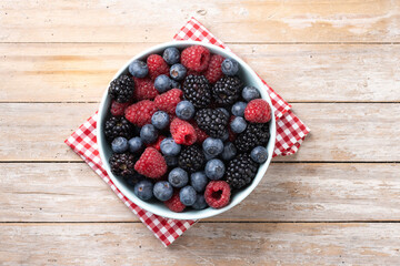 Fresh assortment berries in bowl on wooden table