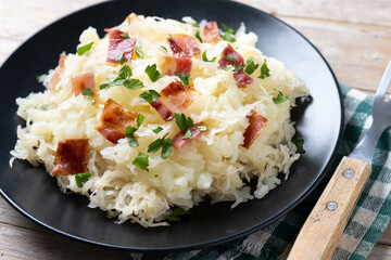 Slovak potato dumplings halusky with steamed sauerkraut and bacon on wooden table
