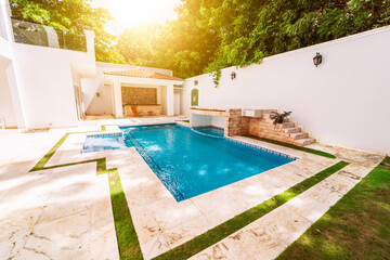 Homemade swimming pool surrounded by trees. Beautiful crystal clear swimming pool in a backyard. Concept of domestic swimming pool designs