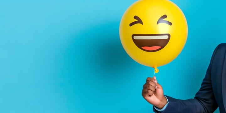 Man in suit holding a yellow balloon with a laughing emoji on a blue background. Concepts. happiness, joy, celebration, humor, and positive emotions