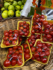 Packaged red cherry tomatoes in a supermarket selling fresh, organic, delicious vegetables and fruits. Vegetables placed on the market shelf in a wicker basket.