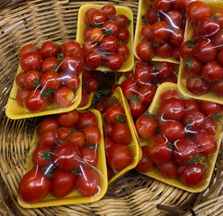 Packaged red cherry tomatoes in a supermarket selling fresh, organic, delicious vegetables and fruits. Vegetables placed on the market shelf in a wicker basket.