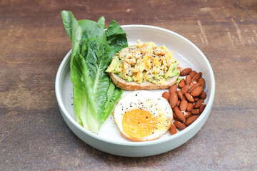 bread with egg and avocado topping with sunny side up egg , lettuce and almond
