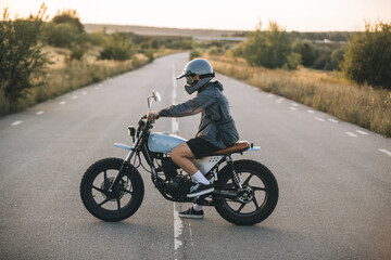 Motorcyclist on custom motorcycle on empty road, sunset. The concept of freedom and riding a motorcycle.