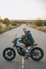 Biker on a cafe racer motorcycle on the road at sunset. Concept of riding a motorcycle at sunset.