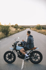 Obraz premium Motorcyclist on custom motorcycle on empty road, sunset. The concept of freedom and riding a motorcycle.