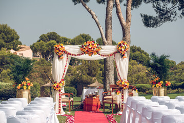 Outdoor wedding setup with floral arch and red aisle