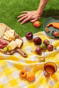 Summer picnic setup with fruits, cheese, and meats on grass