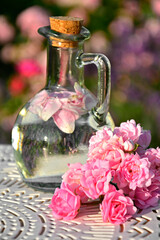 woda różana w szkalnej butelce z korkiem, woda aromatyzowana płatkami róży w butelce, rose water in a glass bottle, water flavored with rose petals in a bottle, Rose water in a glass bottle  © kateej