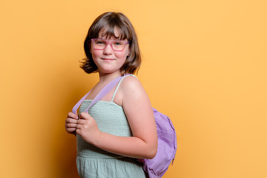 Schoolgirl with glasses and backpack smiling in studio