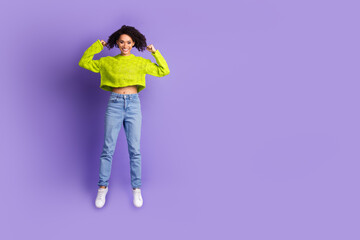 Full body photo of attractive young woman jump show biceps dressed stylish green clothes isolated on violet color background