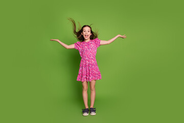 Full body portrait of lovely schoolgirl throw hair wear pink dress isolated on green color...