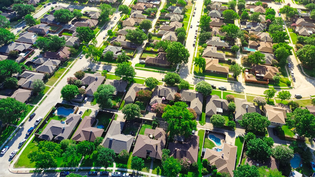 Large two-story suburban houses with swimming pool in upscale residential neighborhood North of Dallas, Texas, lush greenery area of Coppell, DFW Fort Worth metroplex urban sprawl, aerial view