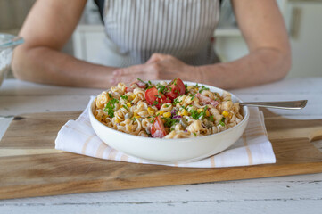 Fresh vegetarian pasta salad with tomatoes, corn, pickles and onions. Delicous homemade summer food
