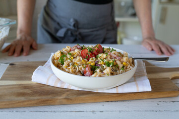 Fresh vegetarian pasta salad with tomatoes, corn, pickles and onions. Delicous homemade summer food