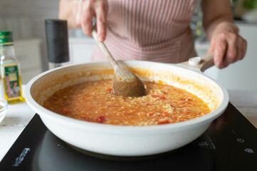 Homemade food. Woman preparing a fresh cooked risotto with tomatoes in the kitchen