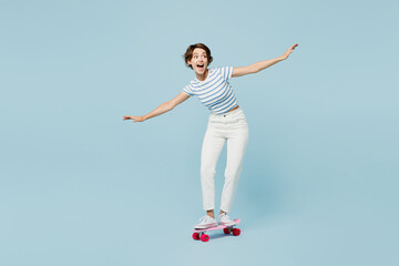 Full body young young woman wearing striped t-shirt casual clothes riding pink skateboard...