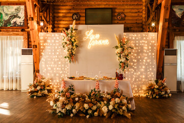young people's table decorated with flowers at a banquet with many light bulbs, wedding.