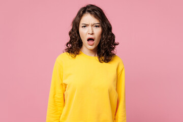 Fototapeta premium Young astonished mad furious sad outraged woman she wearing yellow sweatshirt casual clothes look camera with opened mouth isolated on pastel light pink background studio portrait. Lifestyle concept.