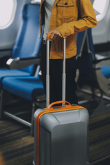Fototapeta premium Young Female Tourist with Luggage Walking Through Airplane Cabin Ready for Travel Adventure