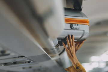 Young Female Tourist Storing Luggage in Overhead Compartment on Airplane During Travel