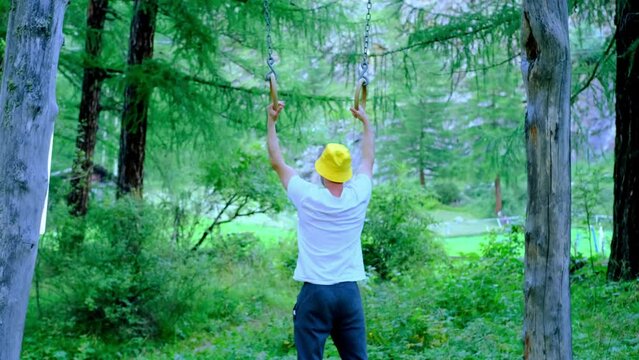 fit young muscular man, 30, doing pull-ups physical exercises, embracing forest air and fitness, peaceful sport outdoors, active lifestyle