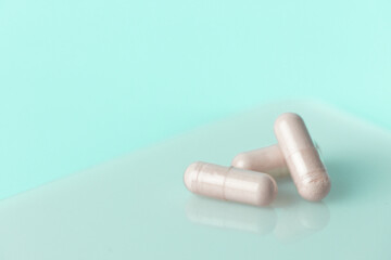 Three pills are sitting on a table. The pills are white and are arranged in a row