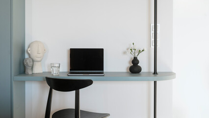 Home office with black chair close to blue desk with laptop computer