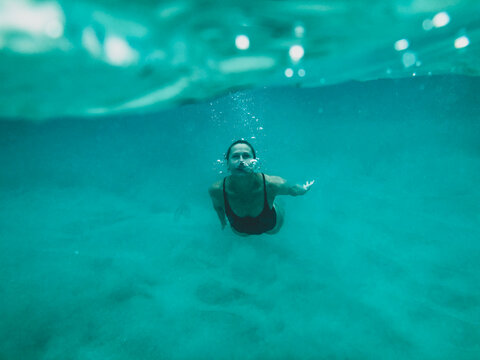 Female swimming underwater in the ocean bubbles coming from nose
