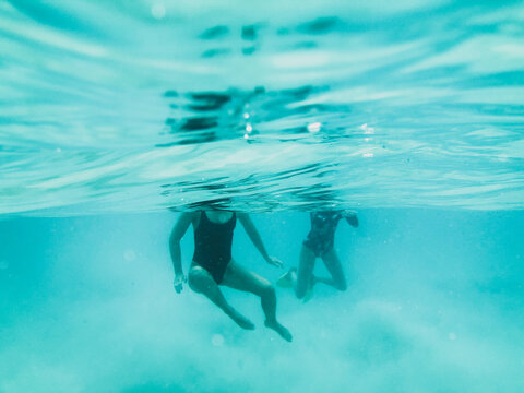Two females diving underwater swimming towards camera in ocean