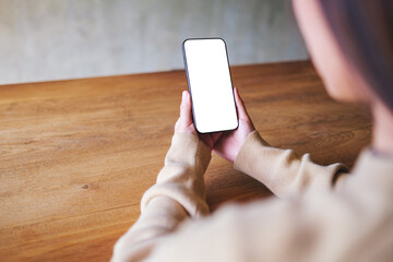 Mockup image of a woman holding mobile phone with blank desktop screen