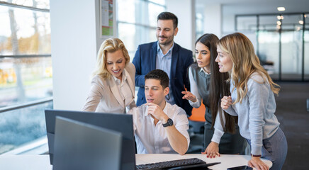 Business professionals collaborate on project using computer at office.