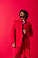 Obraz premium Handsome young Indian man in a striking red suit, exuding confidence and style.