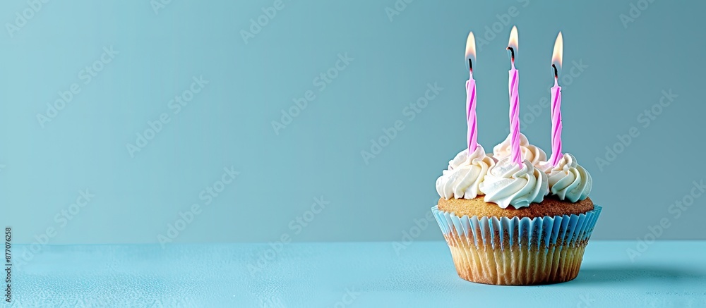 Poster A birthday cupcake with pink candles against a blue backdrop, ideal for adding text or graphics with copy space image.