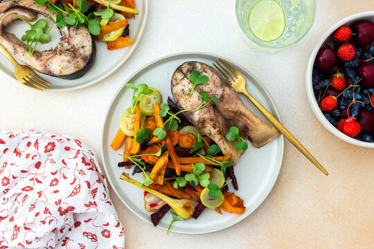 Enjoy baked silver carp with a medley of roasted vegetables including carrots, zucchini, beets, and garlic, paired with fresh seasonal fruits such as cherries, strawberries, and honeysuckle