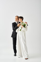 Middle-aged bride and groom in wedding attire pose passionately, radiating joy and love in a studio setting.
