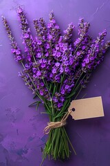 Lavender flowers adorned with a blank tag, placed on a purple surface, offer a calming visual suitable for various designs and messages