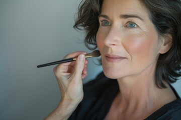Obraz premium aging with grace - mature woman applying anti-aging makeup, beauty and confidence, cosmetics, copy space, neutral color palette