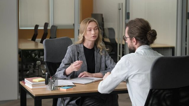 Two professional person having important meeting. A woman takes notes while listening attentively to her male colleague.