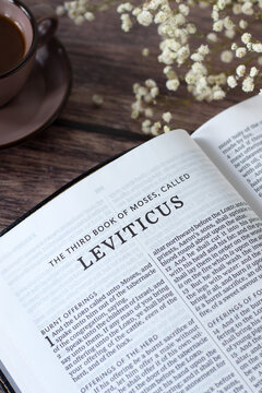 Leviticus holy bible book with cup of coffee on wooden table. Studying old testament Scriptures, Christian biblical concept.