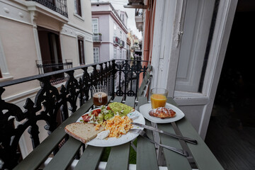 Breakfast with scrabled eggs, coffee, orange juice and avocado toast on the balcony in Spanish old town