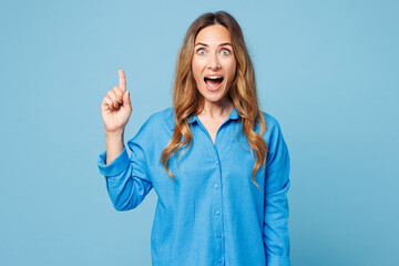 Young surprised shocked woman wears shirt casual clothes holding index finger up with great new idea looking camera isolated on plain pastel light blue background studio portrait. Lifestyle concept. © ViDi Studio