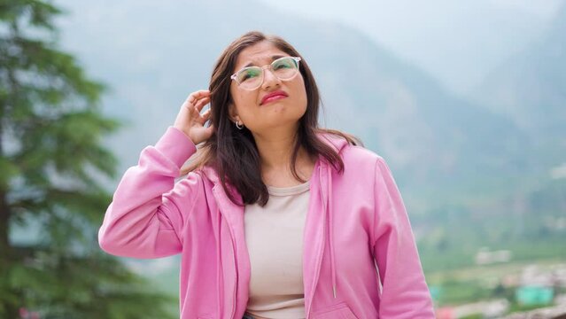 4K Portrait of forgetful Indian girl scratching head in confusion and looking upwards. Forgetful teenager girl student. She is unsure about answer, having doubts, difficult career choice